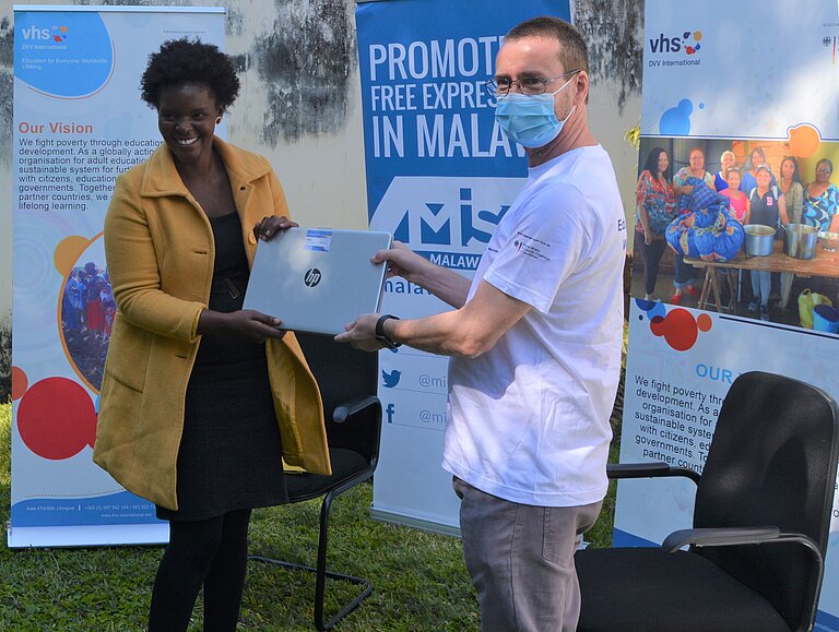 Wezzie Gausi erhält den Laptop von David Harrington, Regionalleiter DVV International Südliches Afrika