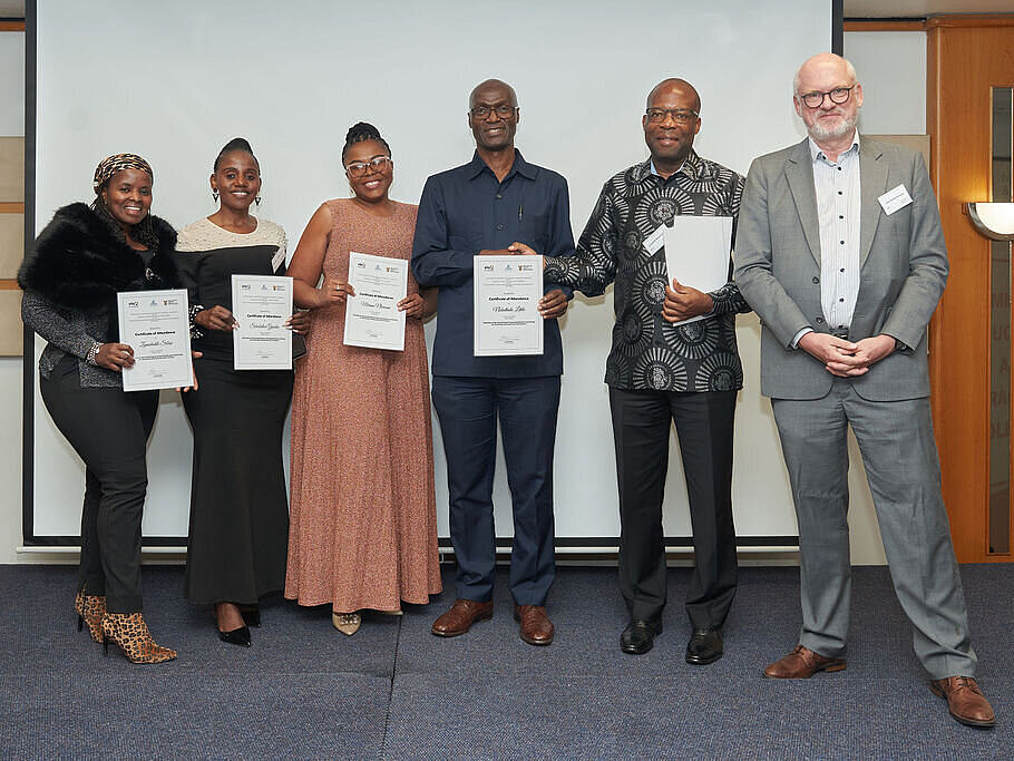 Personen halten jeweils ein Zertifikat und lächeln in die Kamera.