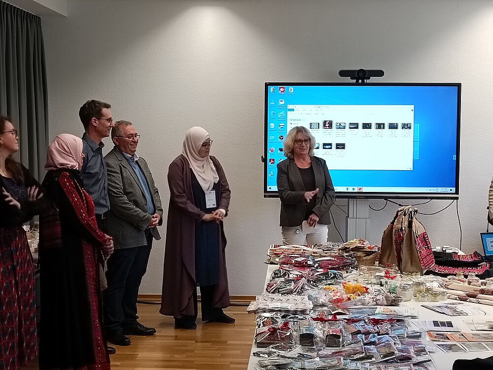 People behind a long table with arts, handicrafts and small gifts on it
