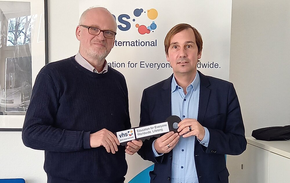 Uwe Gartenschlaeger and Christoph holding the DVV International logo