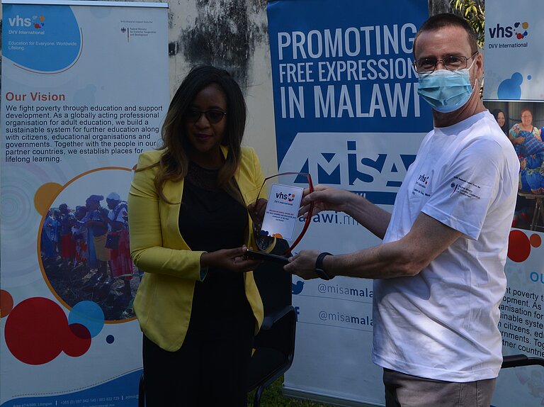 Brenda Kaonga erhält die Trophäe von David Harrington, Regionalleiter DVV International Südliches Afrika