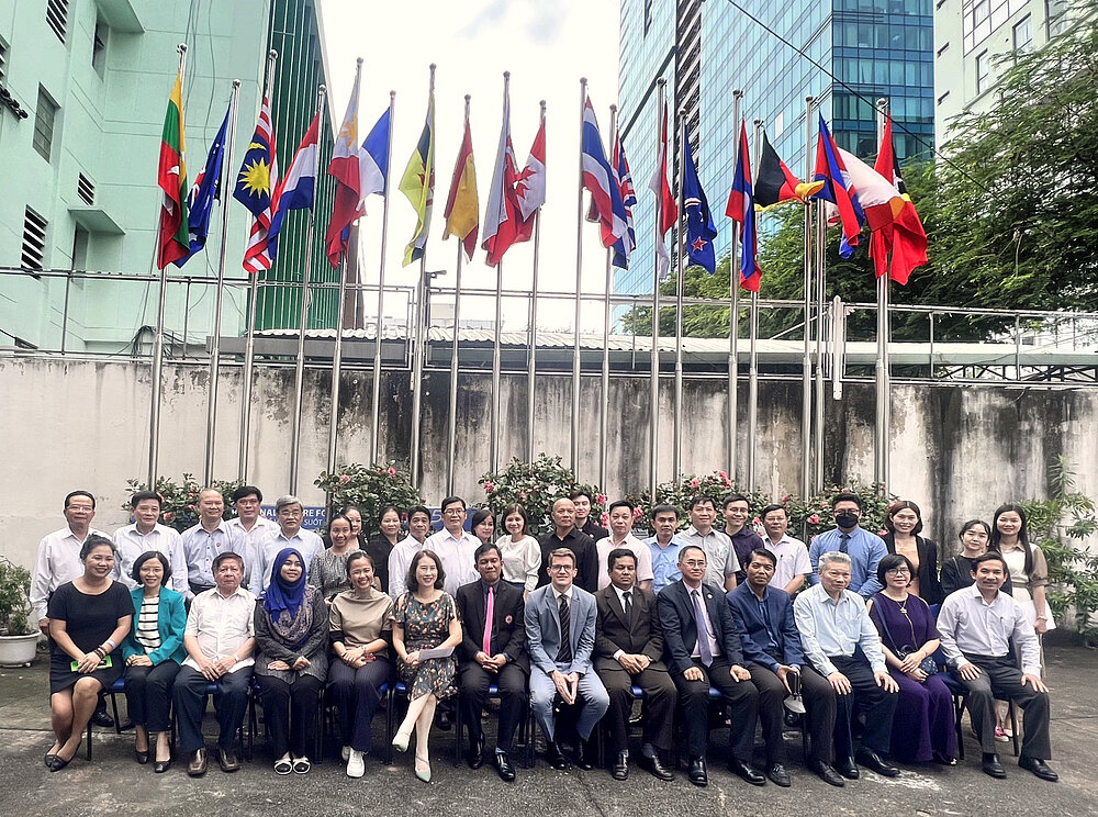 Gruppenfoto von Erwachsenenbildungsexpert*innen vor Flaggen, Ho Chi Minh City