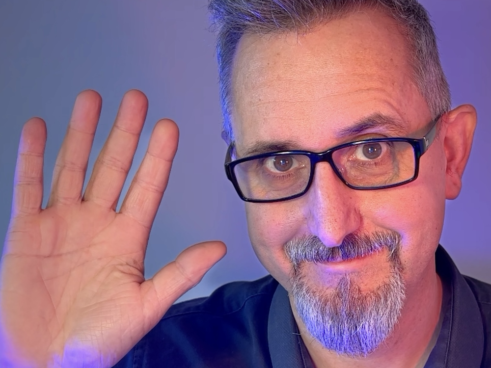 Ein Mann winkt in die Kamera.