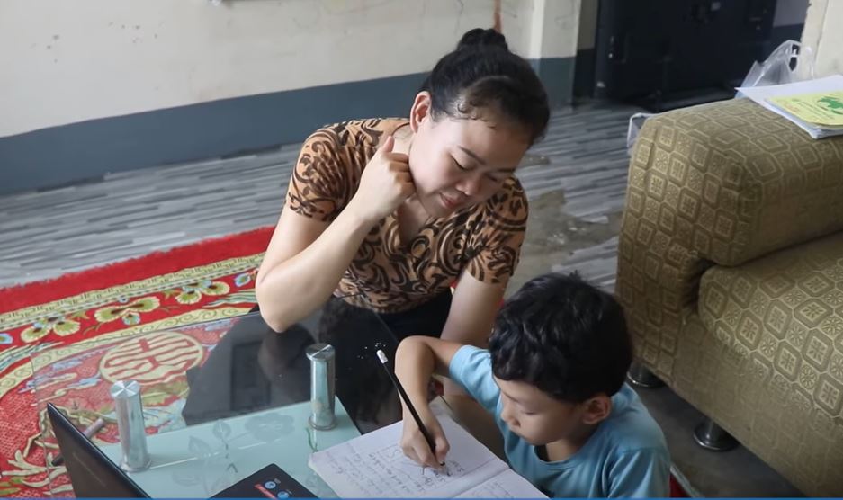 Frau hilft ihrem Kind bei den Hausaufgaben, NFEDC, DVV International